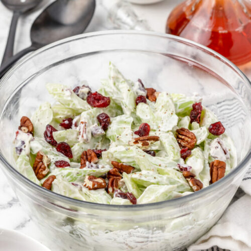 Creamy Celery Salad with toasted pecans and dried cranberries. Large serving spoons on the side ready for scooping.