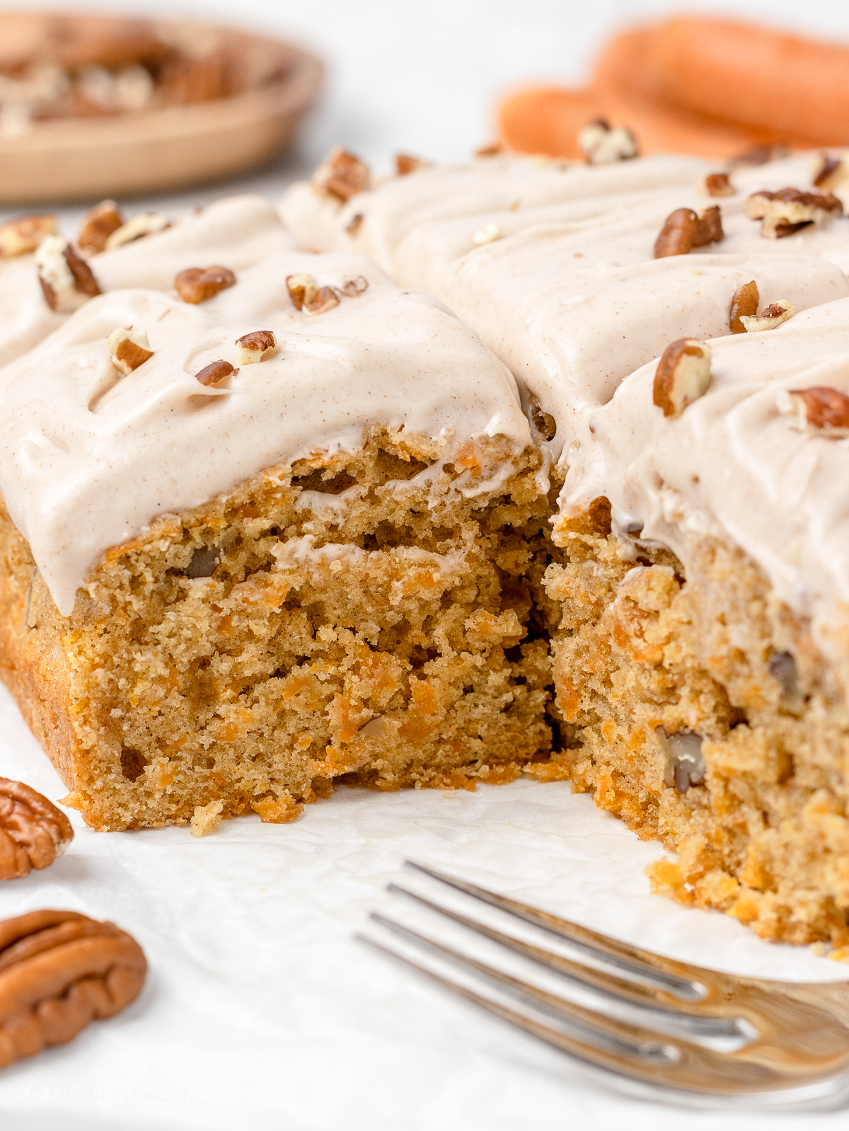A close up of the cake's soft and tender interior. It is filled with shredded carrots and toasted pecans.