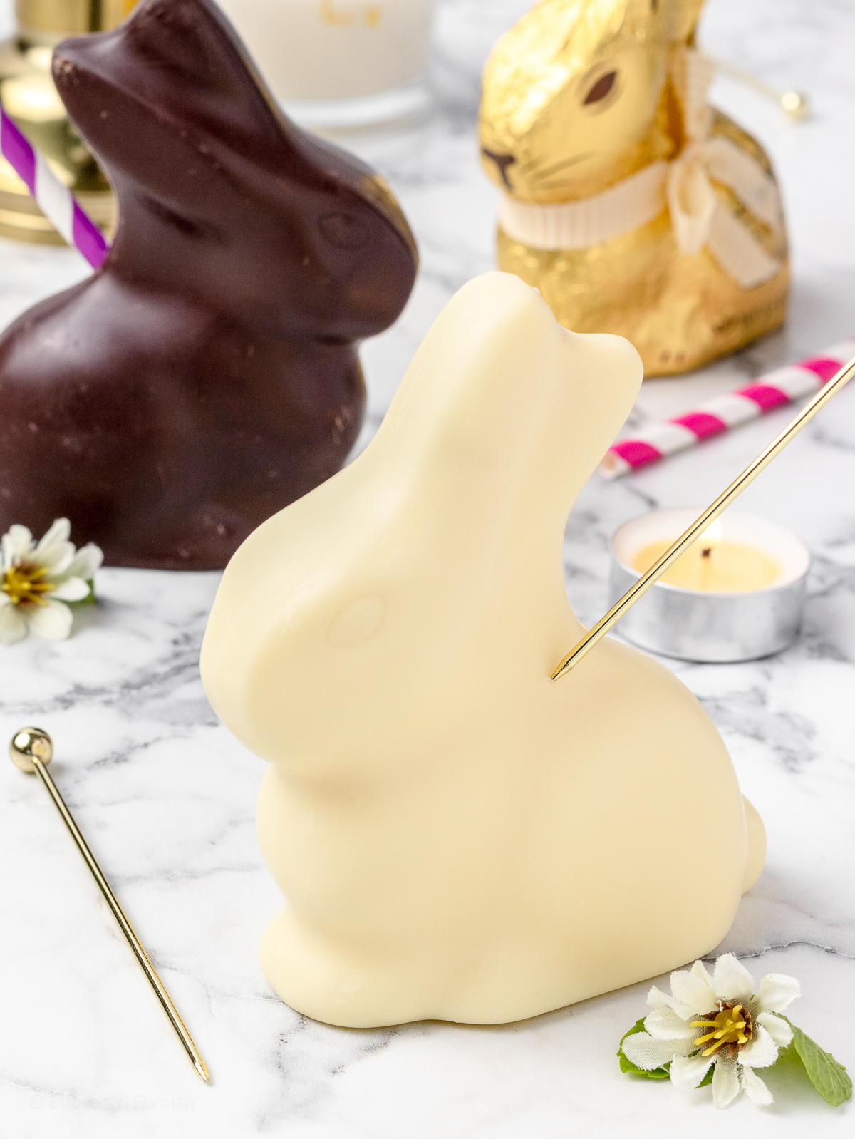 1. Using a small, sharp, metal object to pierce the chocolate bunny and carve out a hole for the small funnel and straw.
