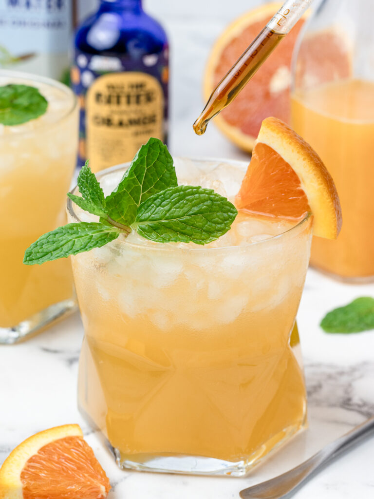 Adding an extra dash of alcohol free orange bitters to the orange and coconut water mocktail.