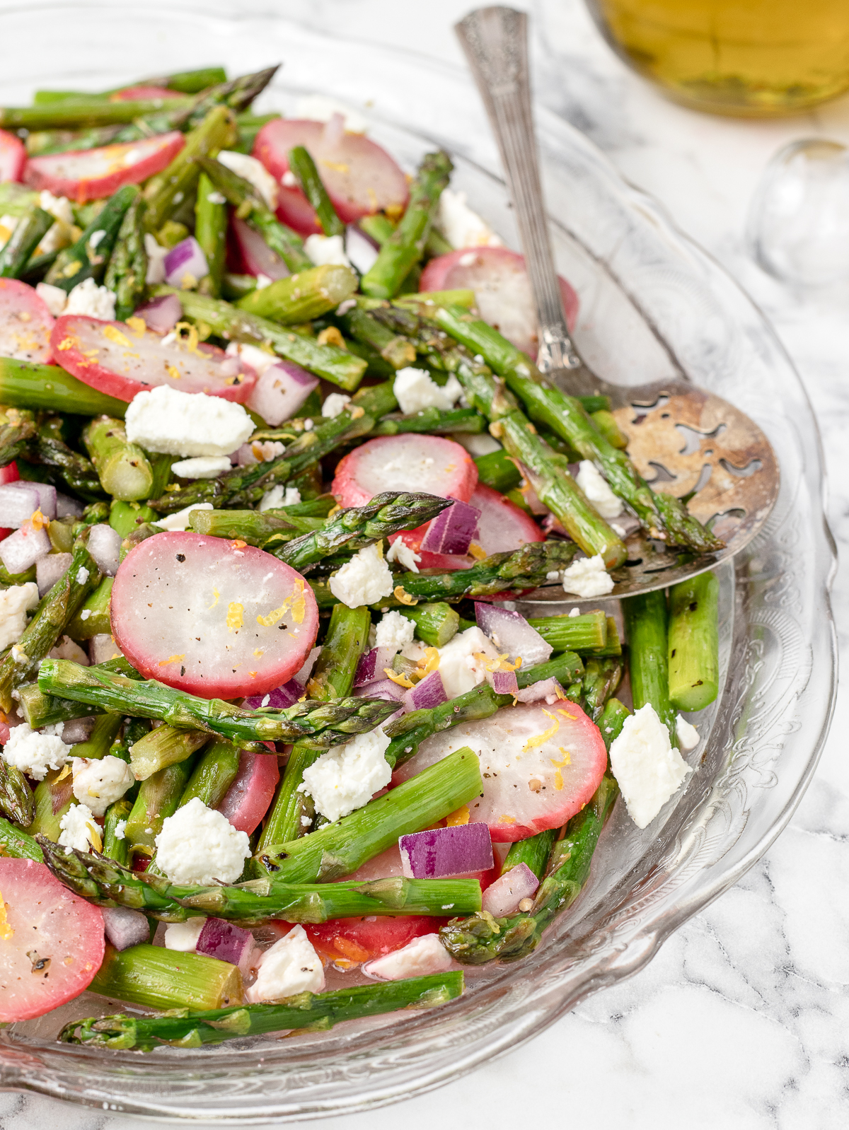 Roasted Asparagus Salad with radishes, feta cheese, and red onion and a big serving spoon for scooping.