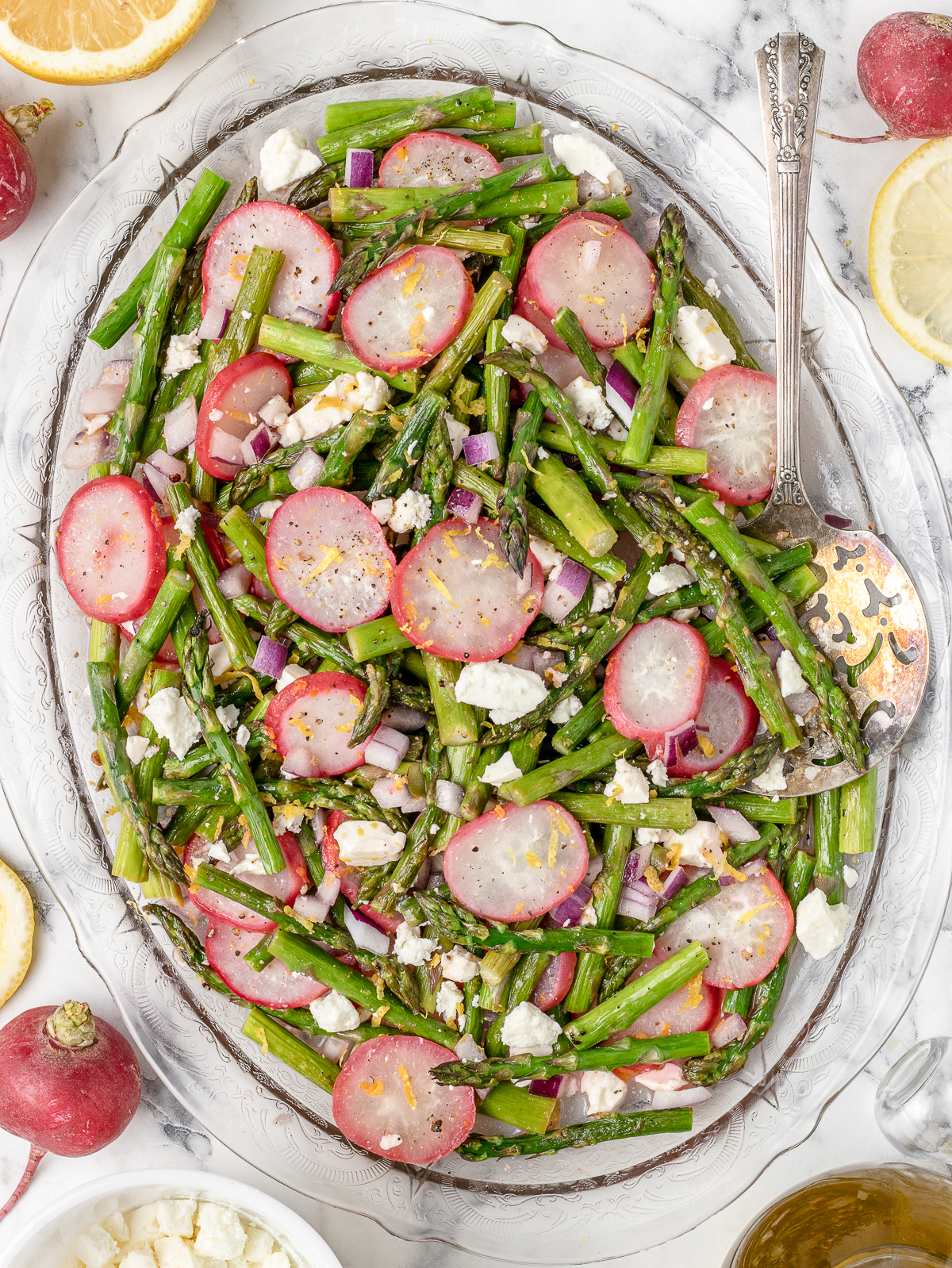 Platter filled with roasted asparagus, radishes, red onion, and feta cheese tossed in lemon juice and lemon zest.