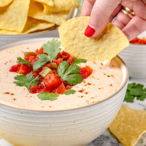 Hand dipping cottage cheese taco dip with a tortilla chip.