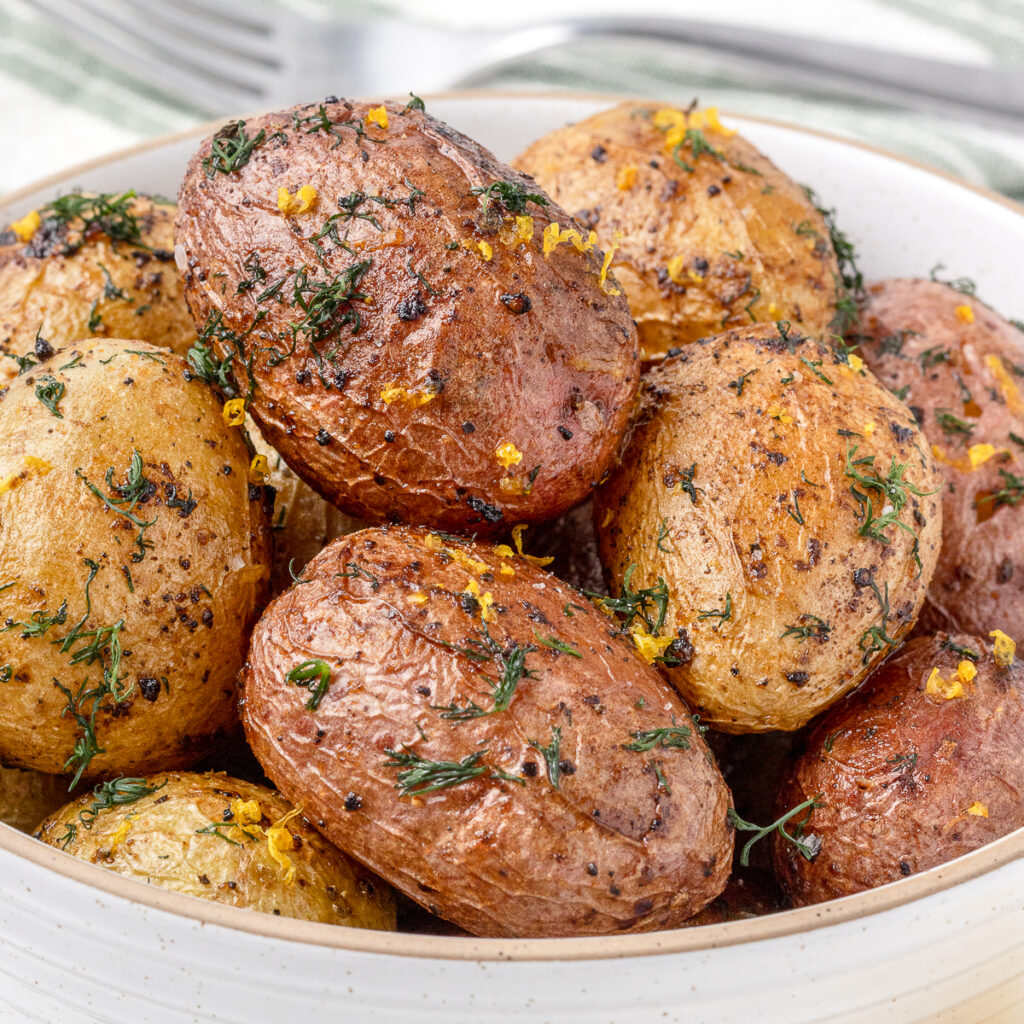 Lemon Dill Potatoes in a bowl ready to eat. They are topped with fresh dill, lemon zest, and super lemony in flavor.