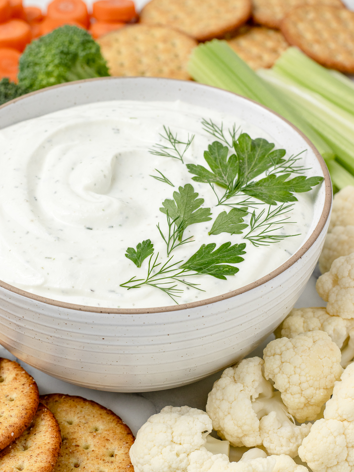Close up of the ranch dip to see it's creamy, thick texture that's spotted with fresh herbs.