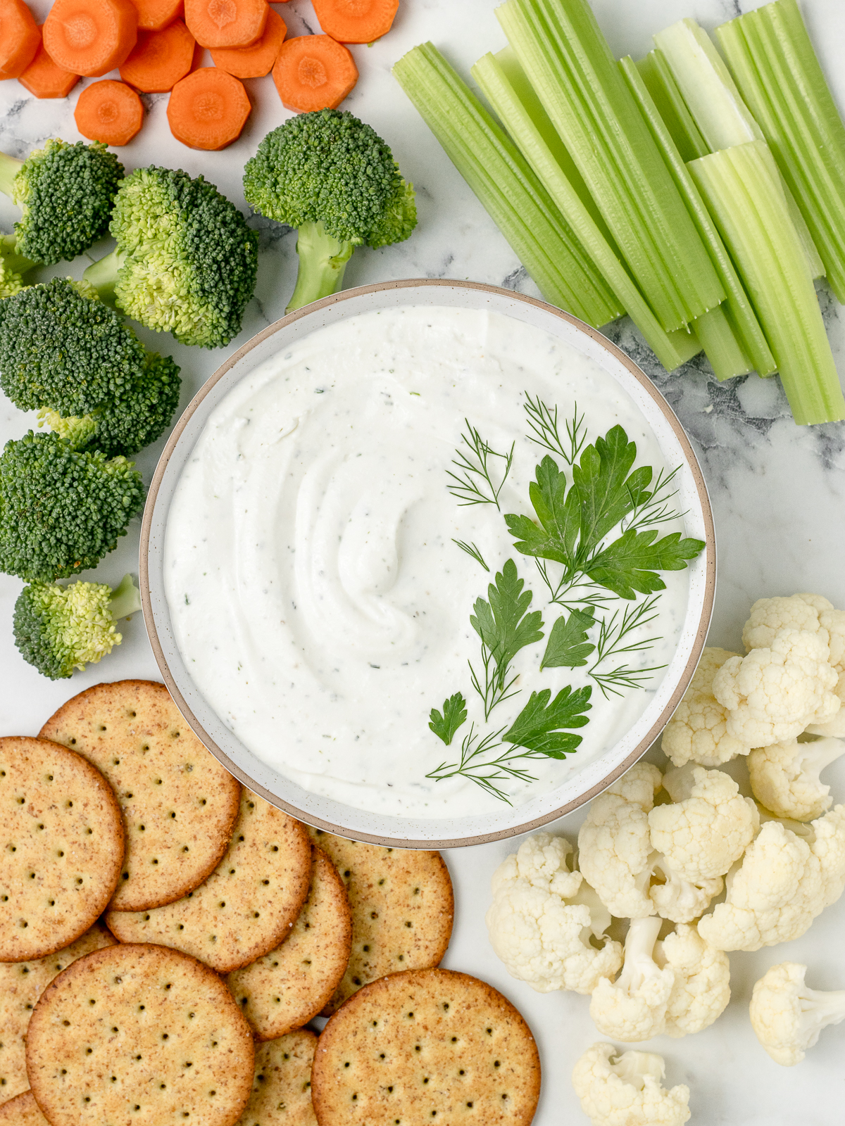 Overhead shot of ranch dip with fresh vegetables and crackers for dipping.