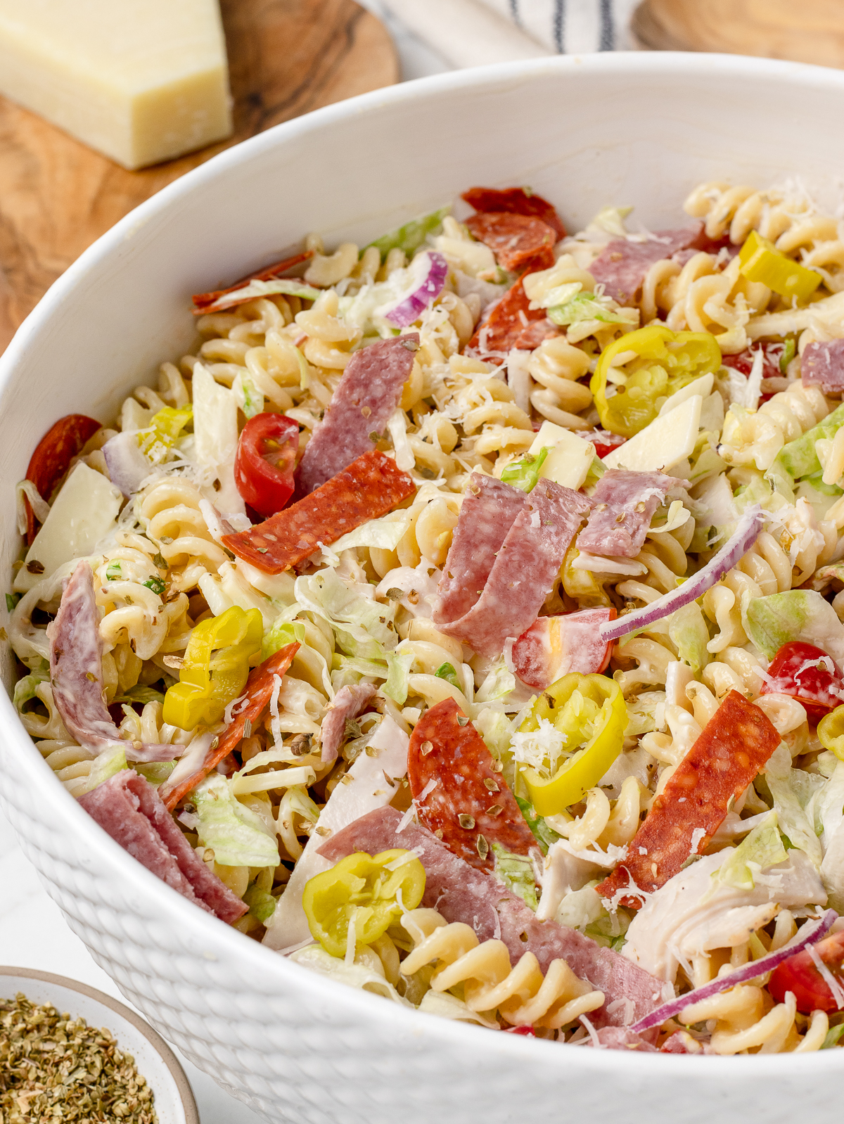 A close up of pasta salad to see all the delicious ingredients including lots of meats, cheeses, vegetables, and a light creamy dressing.