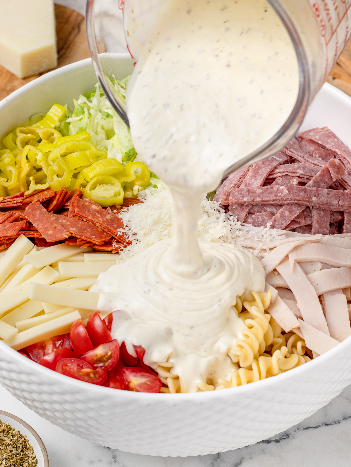 Dressing being poured over the pasta salad.