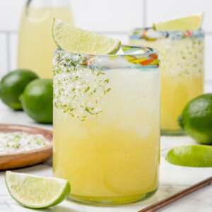 Margarita mocktail in a lowball glass garnished with a salt and lime zest rim with a lime wedge on top.