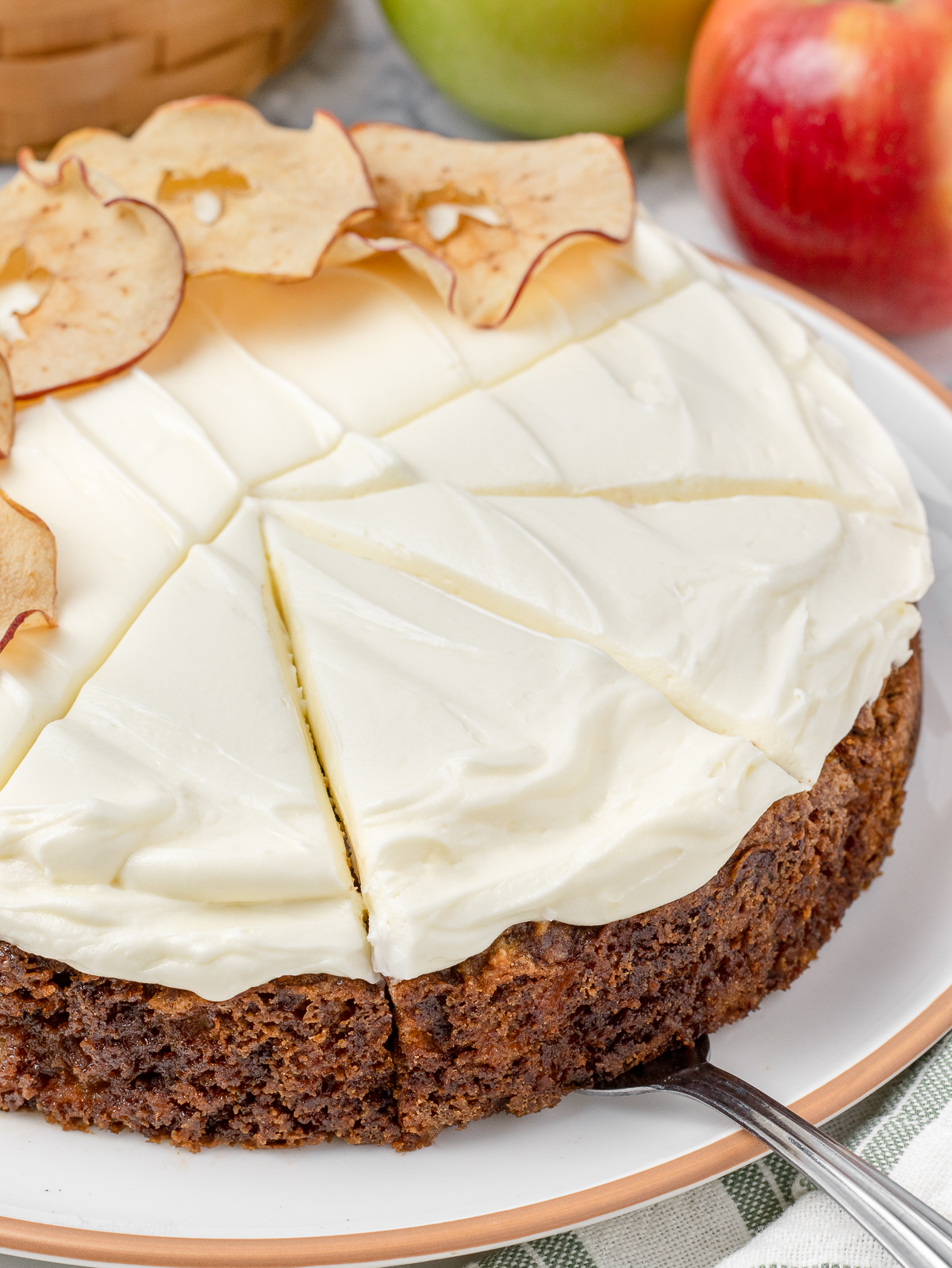 A fork removing a slice of cake to put on a plate and eat.
