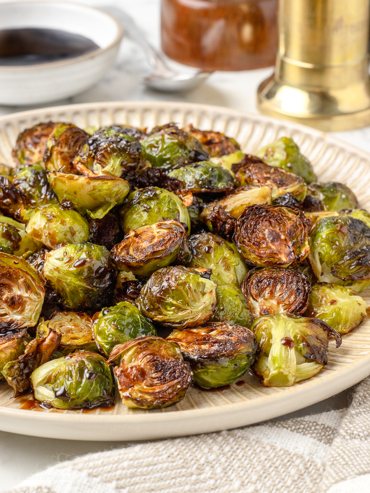 Platter of Balsamic Honey Brussels Sprouts glazed with a balsamic honey sauce. There is more in the background for serving.
