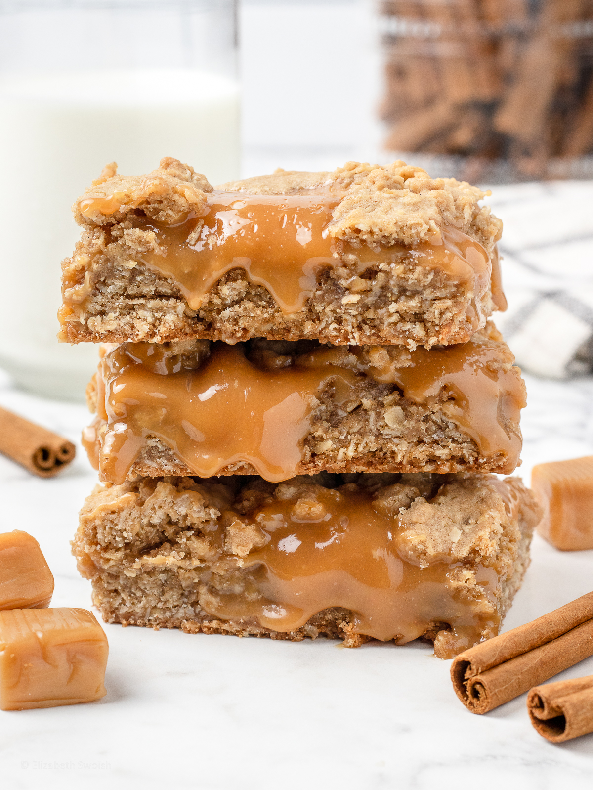 Stack of 3 Caramel Bars. They are cinnamon oat crumble layers with oozing, gooey caramel in the center.