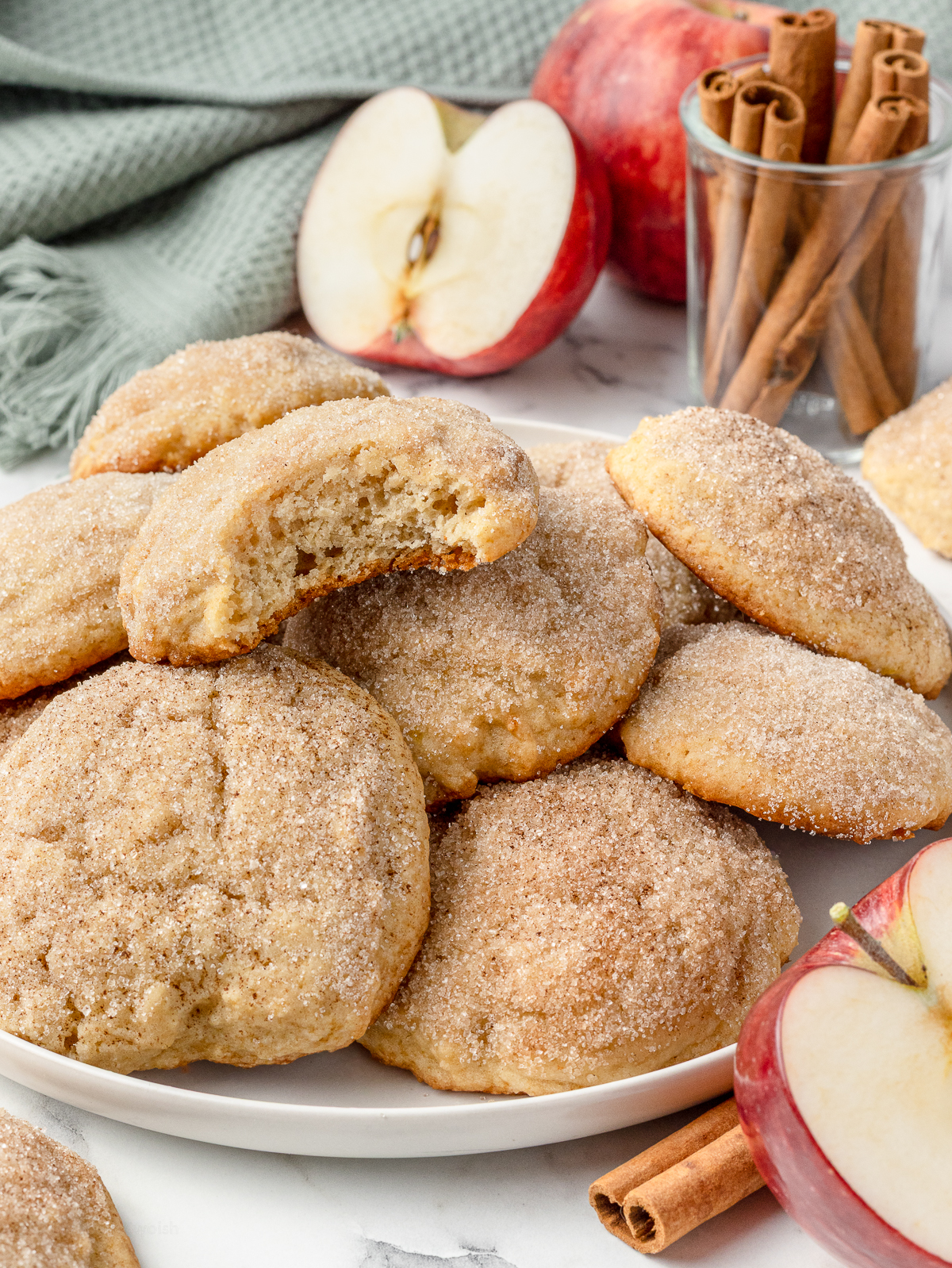 Stack of applesauce cookies. The top one has a bite taken from it and you can see the thick, soft texture along with the cinnamon sugar topping.
