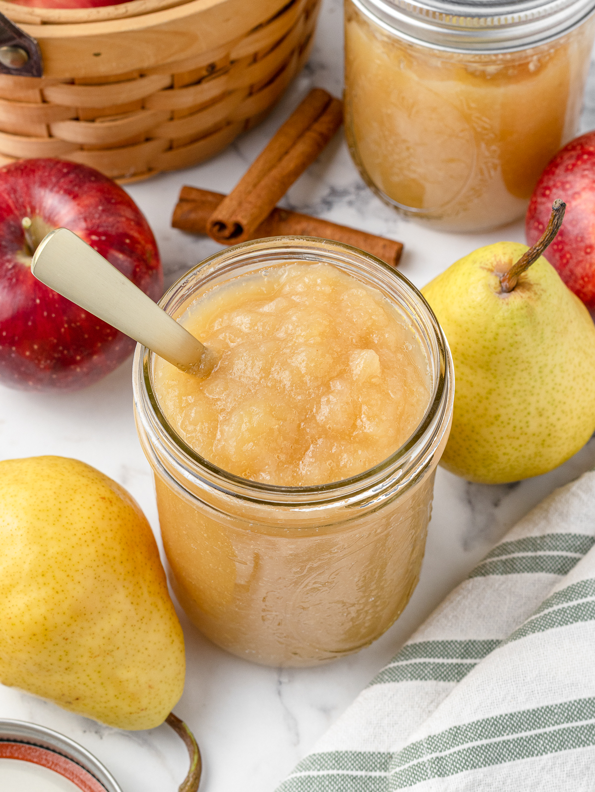 The smooth applesauce with a spoon coming from it. More apples and pears surround it.