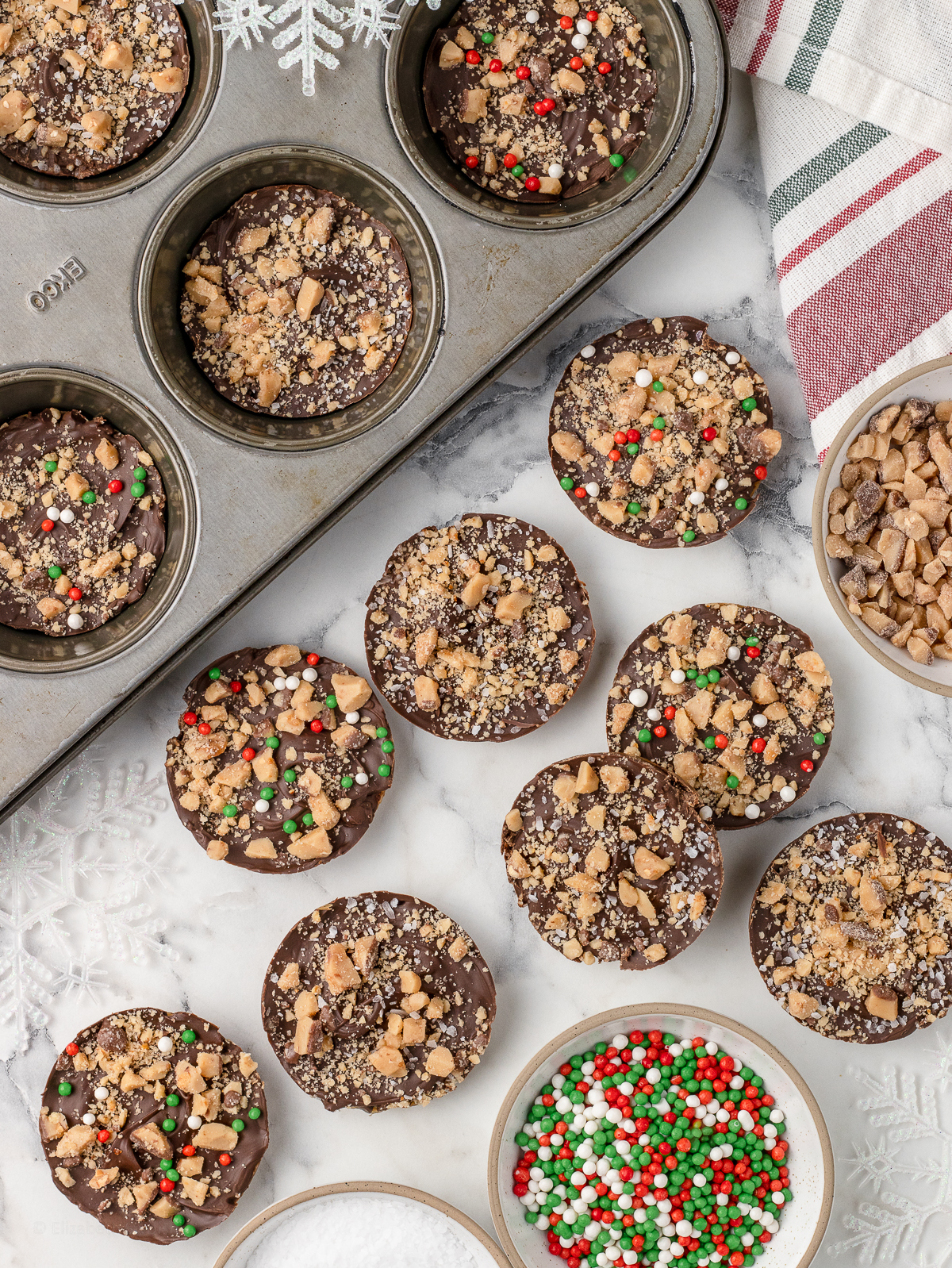 Overhead image of cookies scattered around and others in the cupcake baking pan.