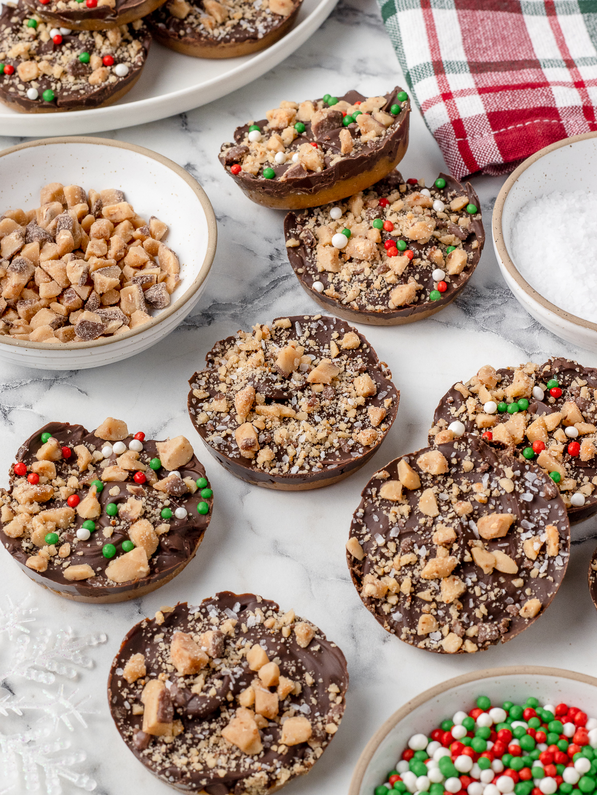 Cookies scattered around. The have toffee pieces, flaky sea salt, and Christmas sprinkles around them.