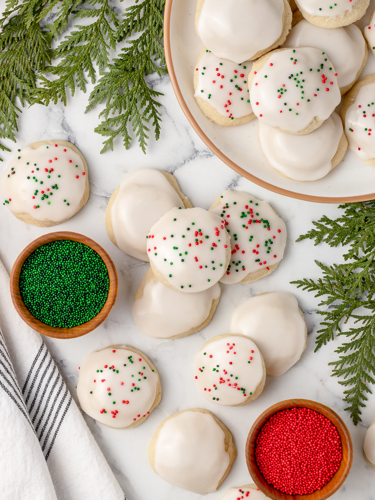 Overhead image of cookies, bowls of red and green sprinkles, plus another plate filled with cookies.