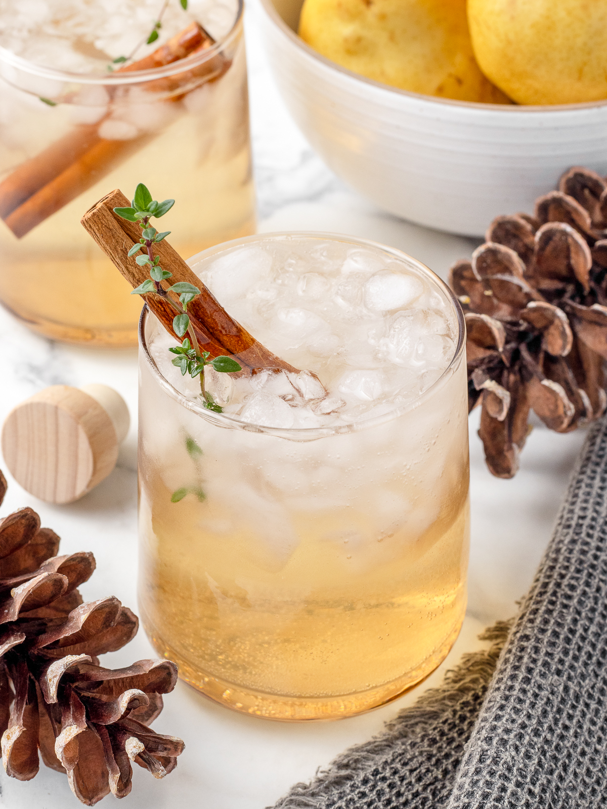 Two shrub drinks with a bowl of pears in the background.