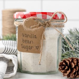 Jar of the vanilla bean flecked sugar with a pretty bow and label that reads "Vanilla Bean Sugar." It is ready for gifting to friends and family.