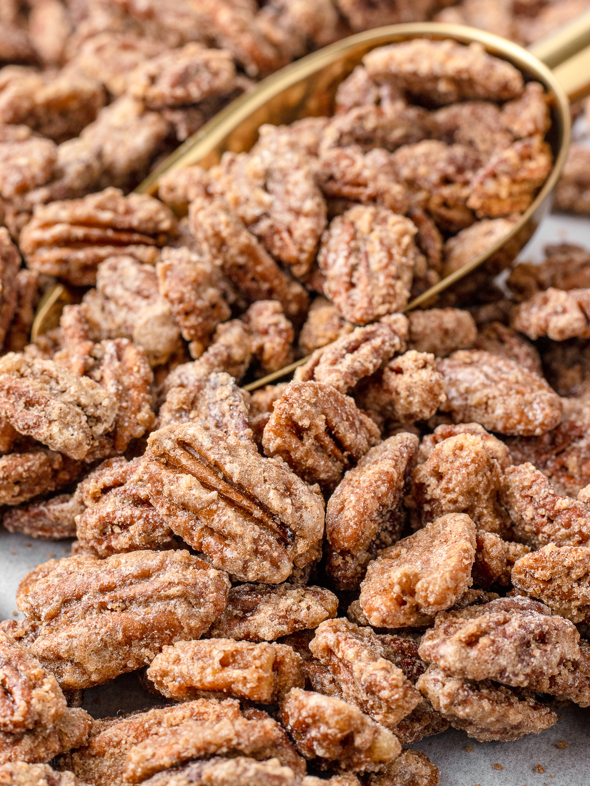 Close up of the Cinnamon Candied Pecans with a gold scoop in the background.
