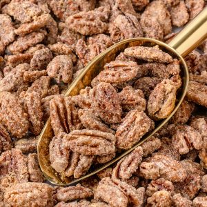 Cinnamon Candied Pecans with a gold scoop in them ready for serving.