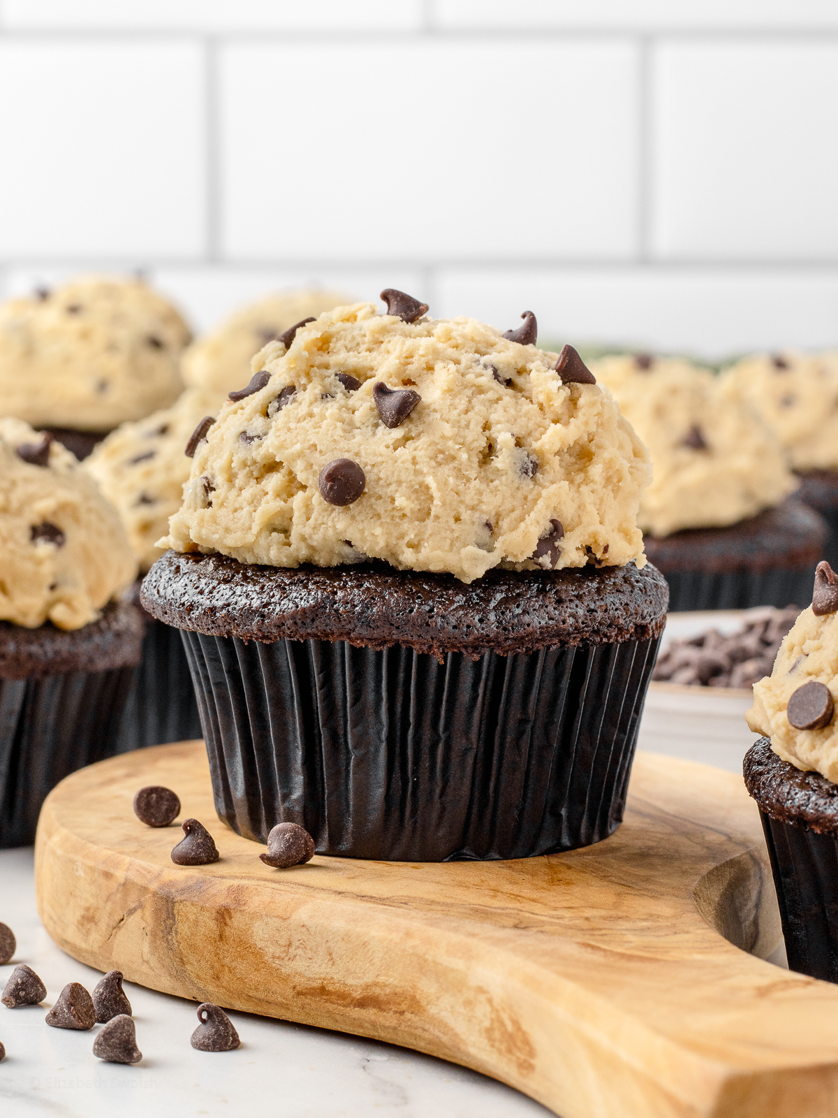 Chocolate cupcakes topped with a thick scoop of chocolate chip cookie dough frosting.