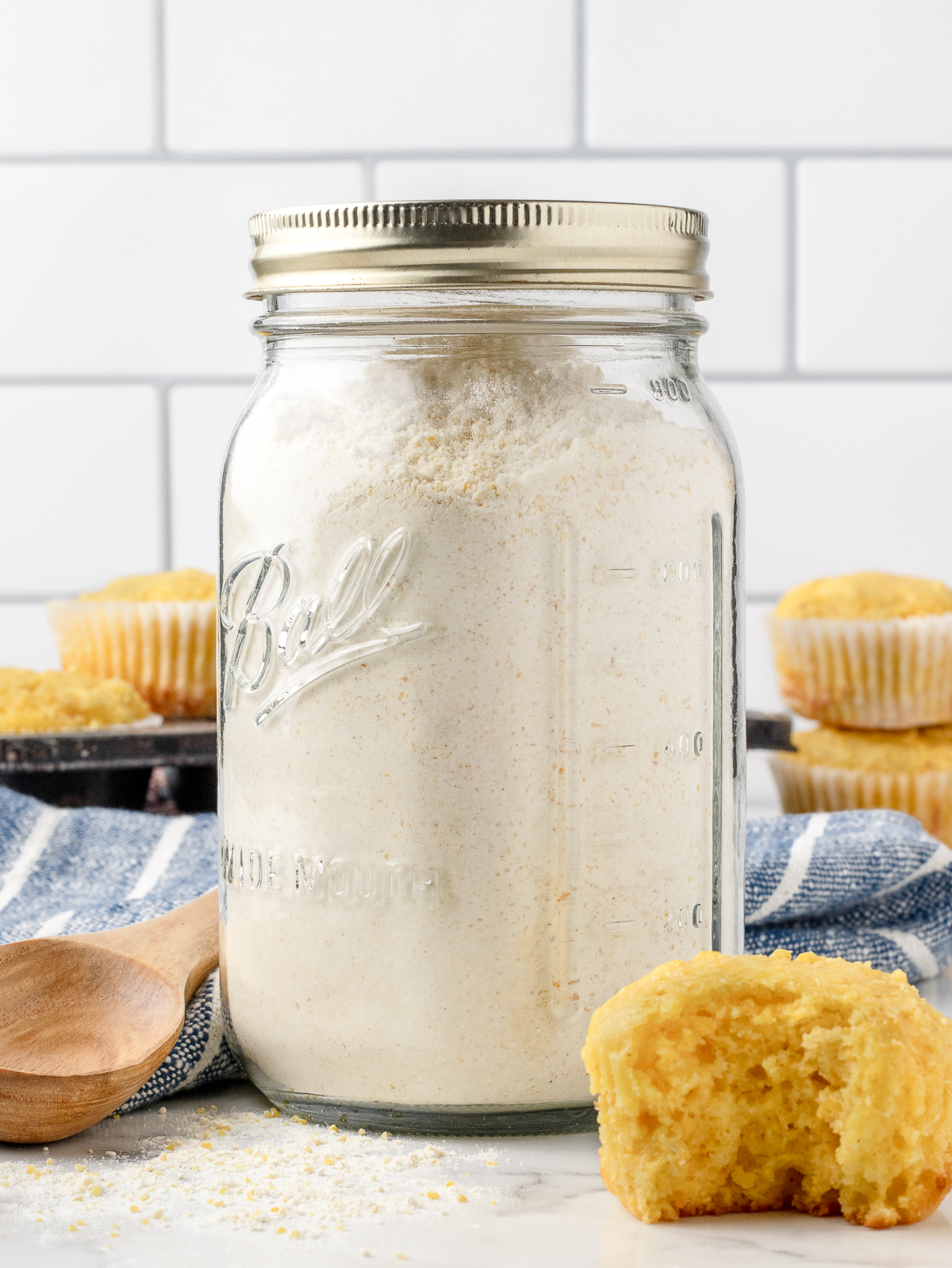 Jar filled with the cornbread mix and ready to use. There are yellow cornbread muffins around.