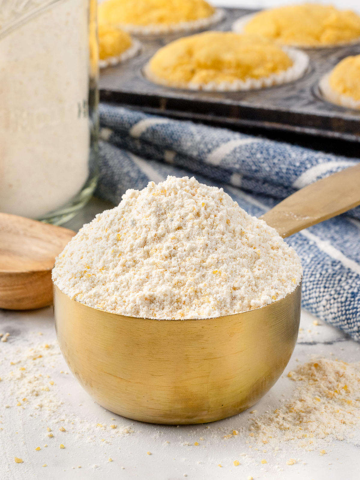 Measuring cup filled with the mix and cornbread muffins in the background.