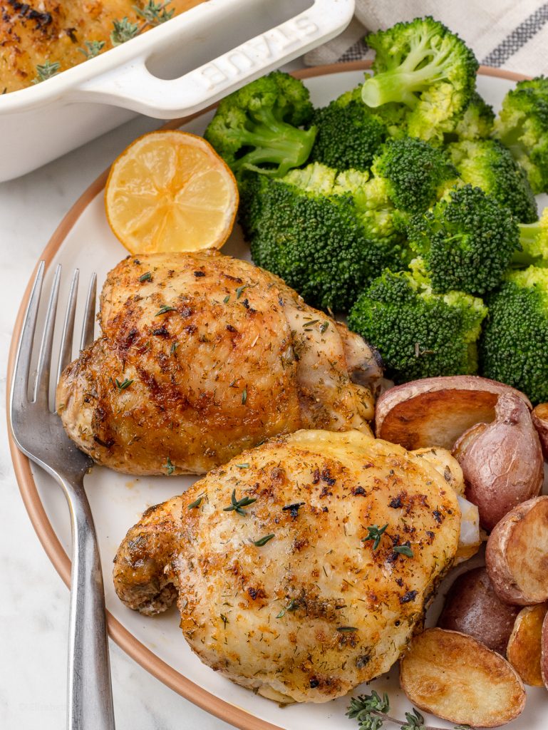 Plate of chicken thighs with steamed broccoli and roasted potatoes ready for eating.
