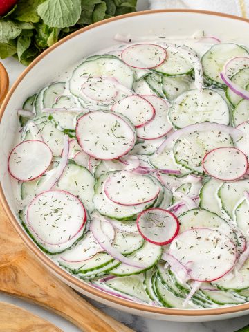 Cucumber Radish Salad tossed in a sweet and creamy dressing with red onion, dill, and black pepper.
