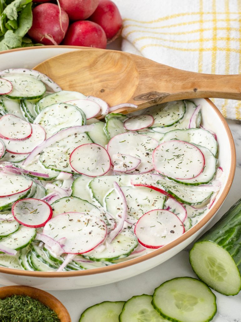 The salad with a big serving spoon in it, ready for scooping and eating.