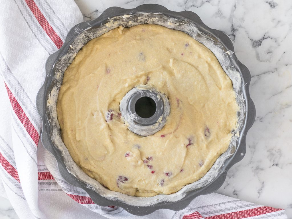 The bundt cake batter in a bundt pan that is prepared with butter and additional flour. It is ready to go in the oven.