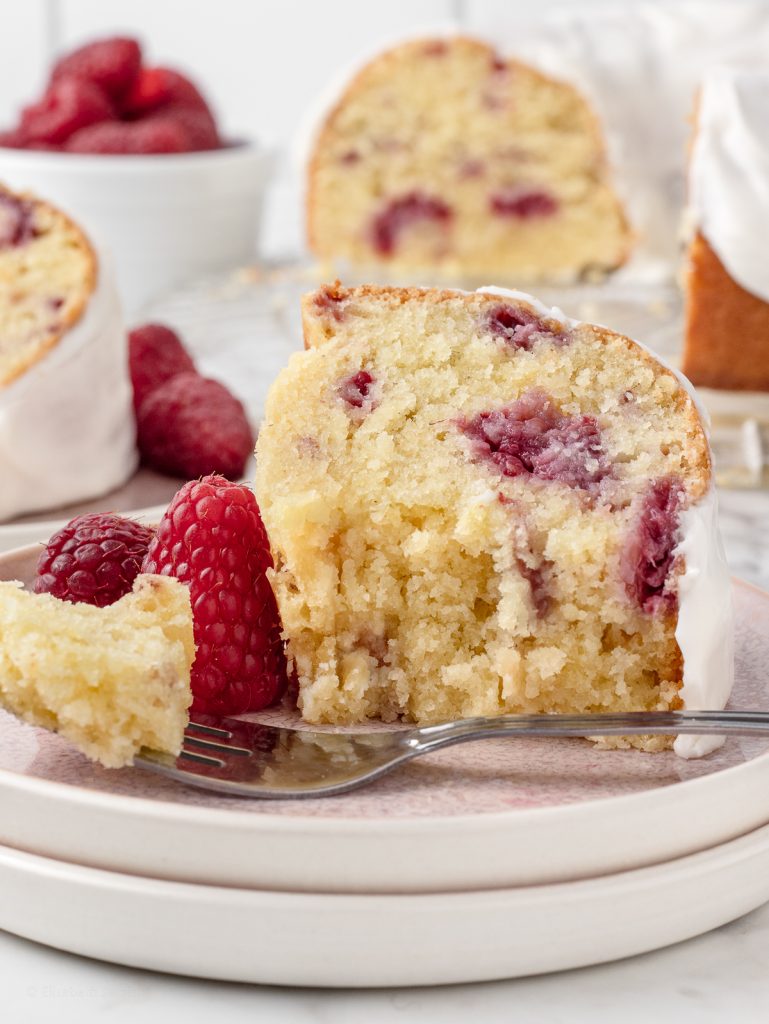 Bites taken from the bundt cake. You can see it's fluffy texture with speckles of fresh raspberry.