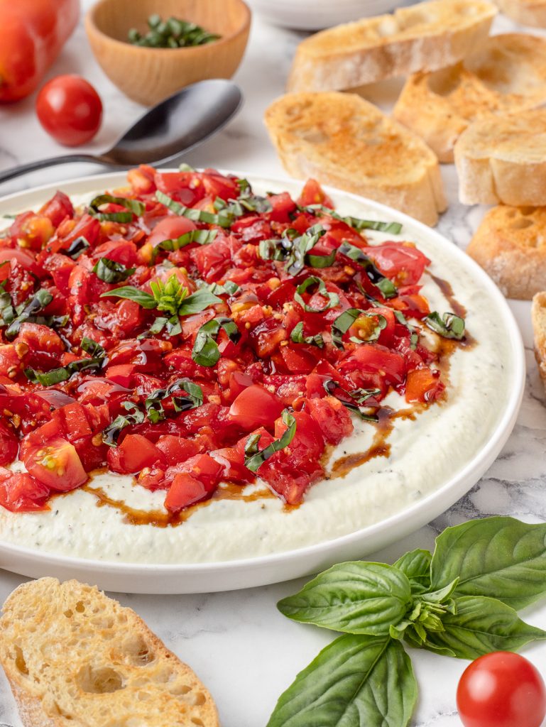 Plate of Bruschetta Dip with crostini on the side for scooping.