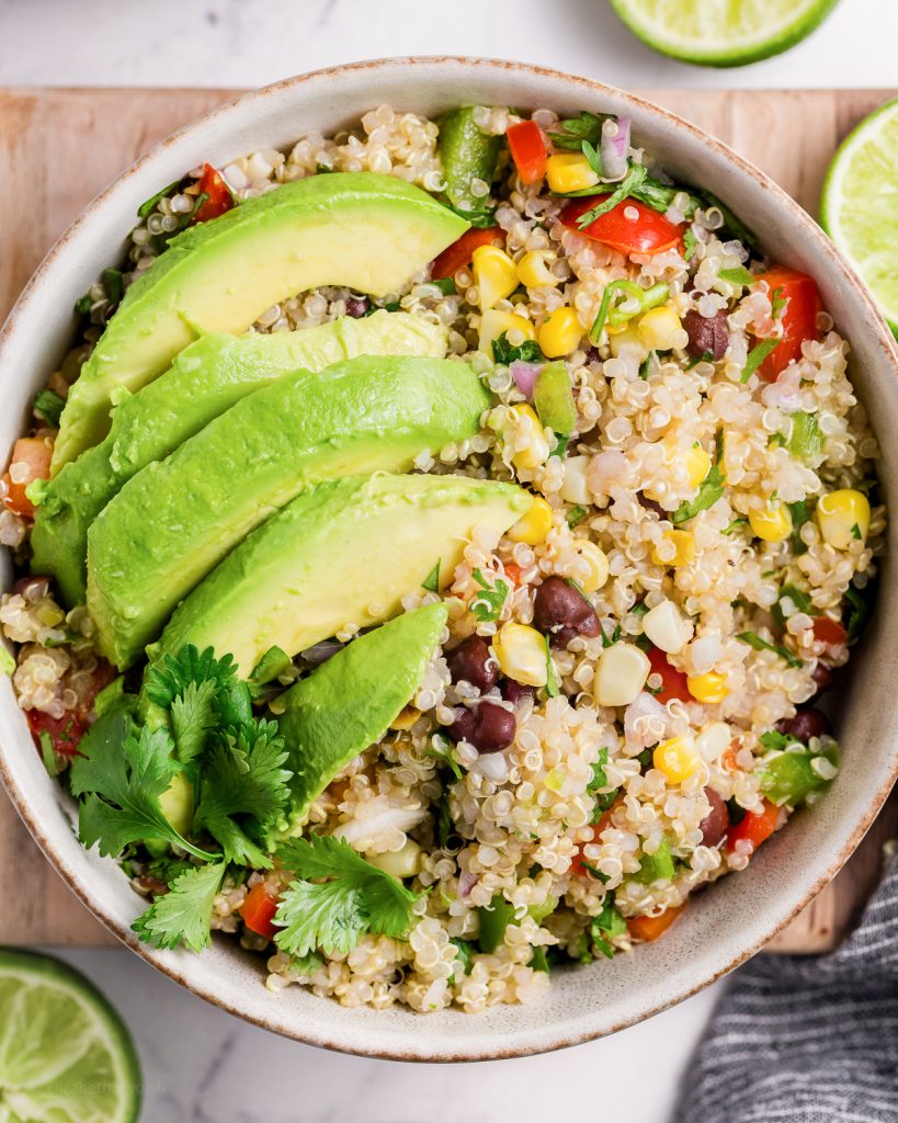 Bowl of quinoa salad topped with avocado and fresh cilantro.